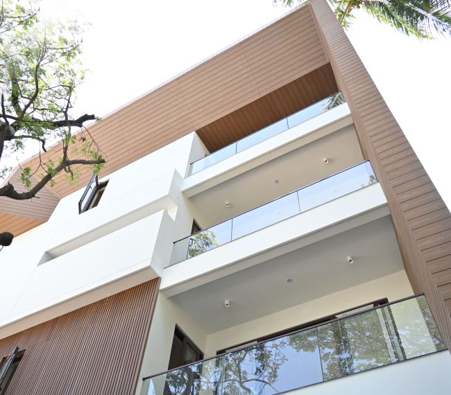 Modern home featuring WPC wall cladding, fluted panels, and glass balconies.